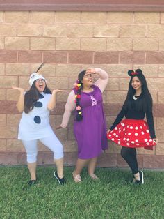 three women dressed up as disney characters posing for the camera in front of a brick wall