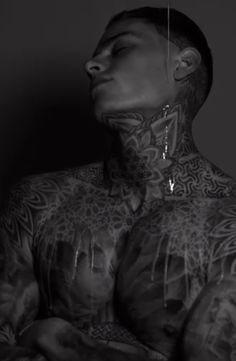 a man with tattoos and piercings on his chest