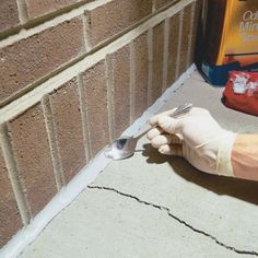 a person in white gloves is holding a fork and knife to the side of a brick wall