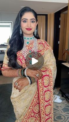 a woman in a red and gold sari posing for the camera with her hands on her hips