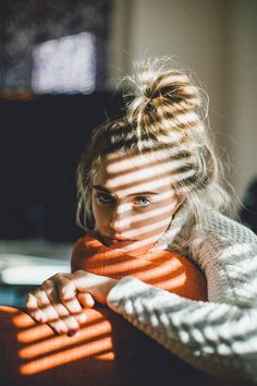 a woman sitting on a couch looking out the window with her hand on her chest