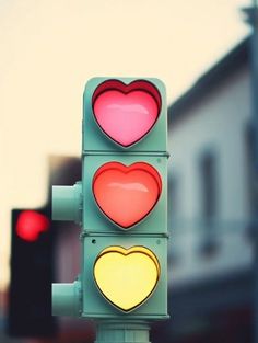 a traffic light with hearts painted on it's red, yellow and green lights