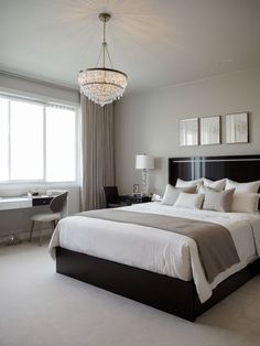 a bedroom with a large bed and a chandelier hanging from it's ceiling