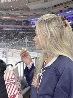 a woman eating food at an ice hockey game