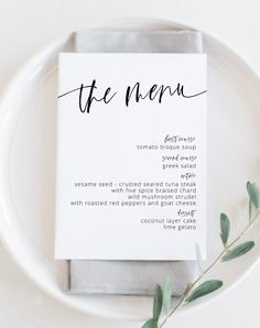 a white plate topped with a menu next to a green leafy plant on top of it