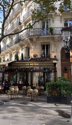 an empty street with tables and chairs in front of a building that has balconies on it