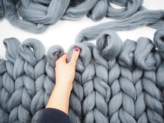 a woman's hand touching the ends of grey yarn