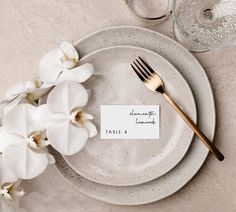 a place setting with white orchids and a name tag on the plate that says sophiie