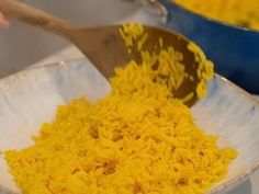 yellow rice in a white bowl with a wooden spoon