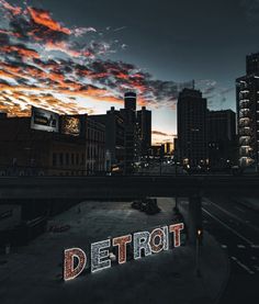 the word detroit is lit up in front of a cityscape at night time