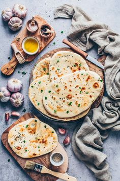 an overhead view of two flat breads on a cutting board with garlic and seasoning