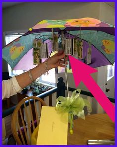 a person holding an open umbrella over a dining room table with a note attached to it