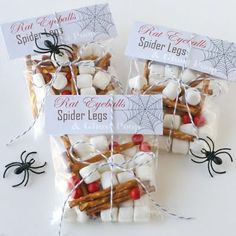 three bags of spider legs and marshmallows on a white surface with halloween decorations