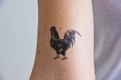 a black and white rooster tattoo on the left arm by a woman's wrist