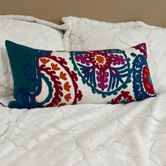 a colorful pillow on top of a white bed