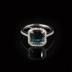 Introducing a stunning Brazilian Green Tourmaline and Diamond Dinner Ring, a timeless piece that exudes elegance and sophistication. This exquisite ring features a gleaming emerald-cut bluish-green Tourmaline, measuring 8.25 x 7.5 MM and weighing an estimated 2 carats. The center stone is beautifully enhanced by a dazzling pave diamond halo (estimated 0.35 carat total weight), with G/H color and SI2 clarity, and additional diamonds adorning the shank. Set in a handcrafted 14K white gold setting, this ring is a size 6.5 (no alterations by the seller).  Tourmaline is a gemstone of extraordinary color, often mistaken for rubies or emeralds before being officially recognized in the 1800s. Few gems can match Tourmaline's vibrant spectrum, with each color holding unique symbolism. Green Tourmali Formal Emerald Halo Ring Fine Jewelry, Gia Certified Tourmaline Rings For Formal Occasions, Formal Radiant Cut May Birthstone Ring, Formal Radiant Cut Ring With May Birthstone, Elegant Emerald Cut Tourmaline Ring, Elegant Emerald-cut Tourmaline Ring, Emerald Cut Gia Certified Sapphire Ring For Formal Occasions, Gia Certified Emerald Cut Sapphire Ring For Formal Occasions, Gia Certified Square Cut Sapphire Ring For Formal Occasions