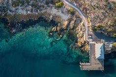 an aerial view of a pier and the ocean with clear blue water in the foreground