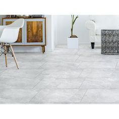 a living room with white furniture and large tiles on the floor, including a chair