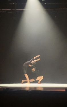 two dancers performing on stage in front of spotlights