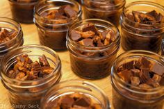 many small glass jars filled with food on top of a wooden table