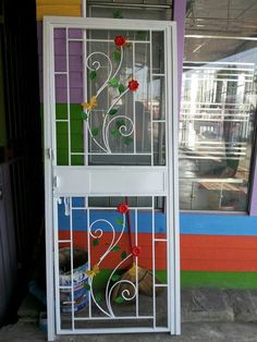 a white door with flowers on it and a window in the background that is painted multicolored