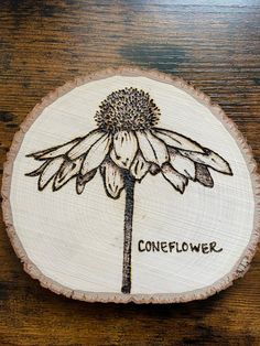 a wood slice with a flower on it and the words coneflower written in black ink