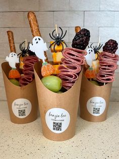 three cups filled with halloween treats on top of a counter