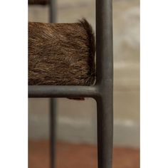 an animal's tail sticking out of the back of a metal chair with bars