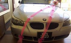 a car is decorated with pink ribbons and bows for the bride's wedding day