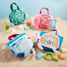 several toys are laying on the sand near each other and one has a beach bag