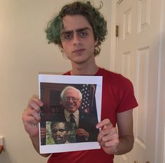 a man with green hair holding up a photo