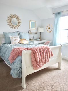 a bedroom with a white bed and blue comforter on top of it, along with a pink throw blanket