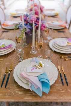 a wooden table topped with white plates and place settings