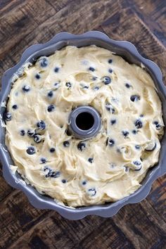 a cake pan filled with batter and blueberries on top of a wooden table next to a knife