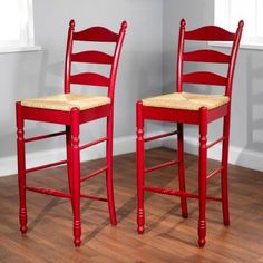 two red chairs sitting next to each other on top of a hard wood floored floor