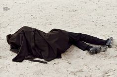 a man laying on the sand with his head down