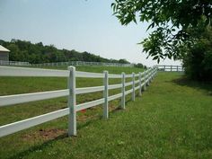 a white fence in the middle of a grassy field