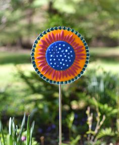 a blue, orange and yellow flower sitting on top of a metal pole