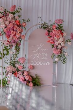 pink flowers and greenery decorate the backdrop for a wedding ceremony