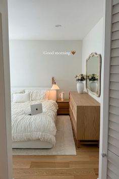 a bedroom with a bed, nightstand and laptop on the table in front of it