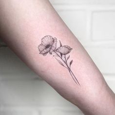 a small flower tattoo on the left inner arm and lower arm, with two petals in black ink