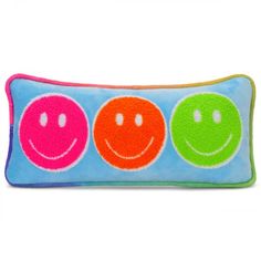 a colorful pillow with three smiling faces on the front and one green, pink, and orange