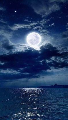 the full moon shines brightly in the night sky over the ocean with calm water