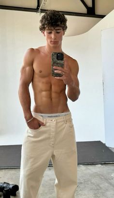 a shirtless man taking a selfie with his cell phone