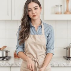 a woman standing in the kitchen with an apron on