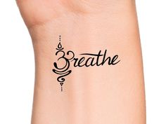 a woman's wrist with the word breathe written in cursive writing on it