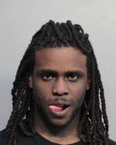 a man with dreadlocks is looking at the camera while wearing a black shirt