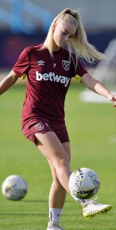 a woman kicking a soccer ball on top of a field