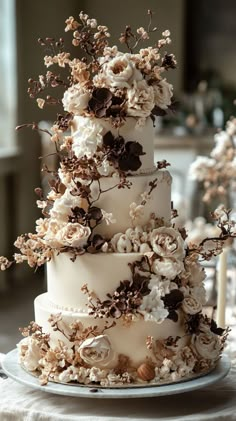 a three tiered cake with white flowers on the top and brown leaves on the bottom