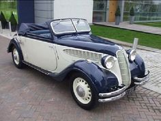 an old car is parked on the side of the road in front of a building